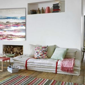 A romantic living room with a painting, soft colors, and cozy furniture.
