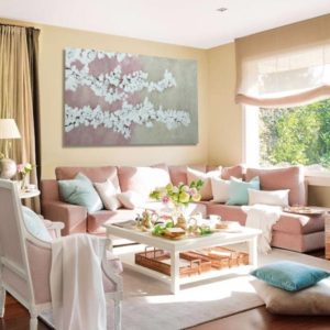 A romantic living room with a painting, soft colors, and cozy furniture.