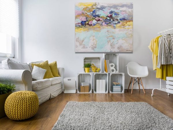 A romantic living room with a painting, soft colors, and cozy furniture.