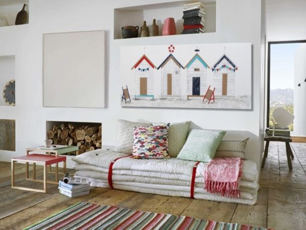 Beach hut painting above a sofa in a living room setting.