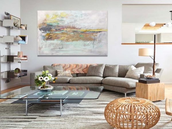 Gold abstract painting above white sofa in a bright modern living room.