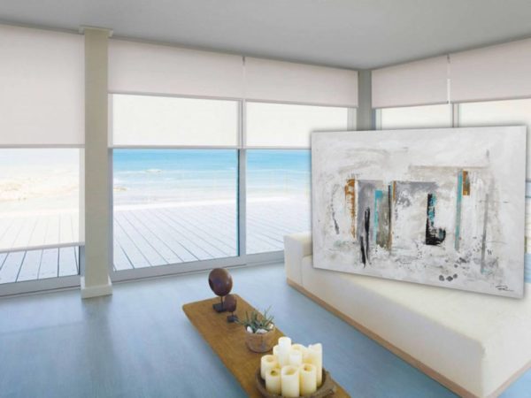 Large sheer roller blinds in a room with ocean view and abstract art.