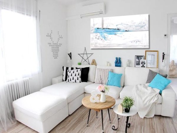 Bright, cozy modern apartment living room with abstract art above a white sectional.