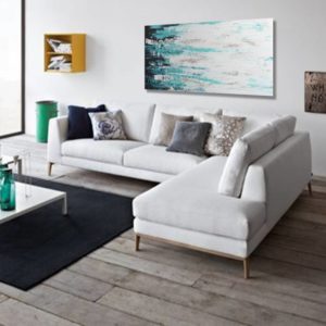 Modern living room with a white sectional and abstract teal art.