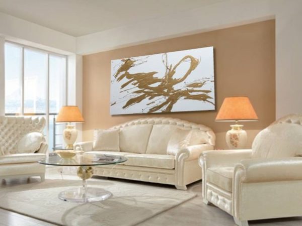 Gold abstract painting above white sofa in a bright modern living room.