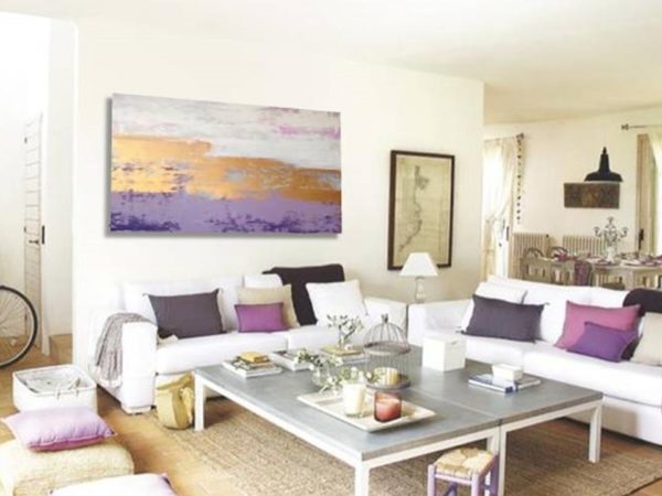 Gold abstract painting above white sofa in a bright modern living room.
