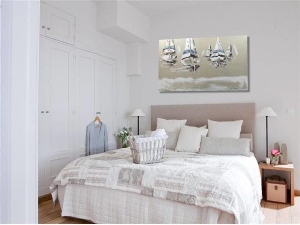 Seascape painting with white sailboats above a bed with a patchwork quilt.