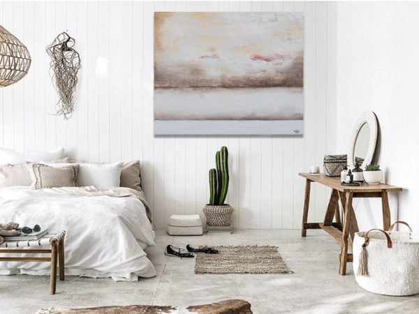 Minimalist bedroom with abstract beige painting and cactus decor.