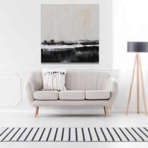 Minimalist black and beige landscape art above a light gray sofa.
