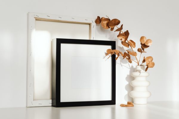 Minimalist framed picture and decorative plant on a table.