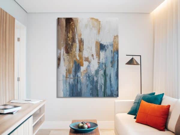 Abstract hand-painted artwork with blues and gold tones above a modern sofa in a minimalist living room.